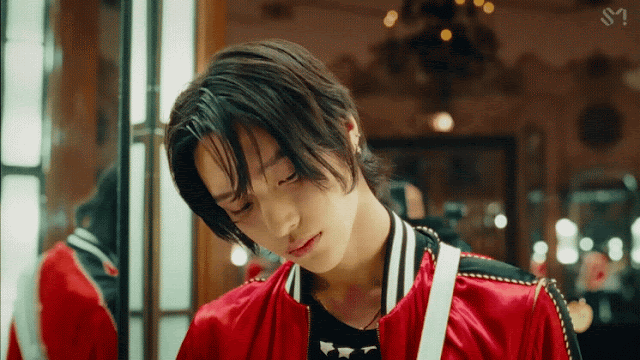 Gif from the music video of Kpop boy group Riize's debut song "Get A Guitar" where Wonbin looks at the camera while standing next to a mirror