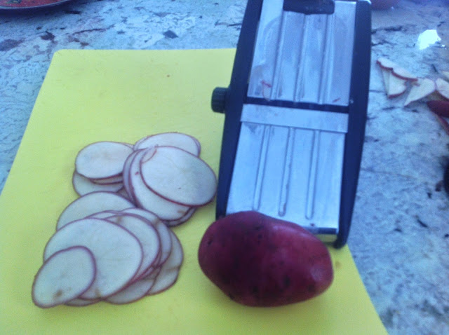 slices of potatoes next to a mandolin slicer