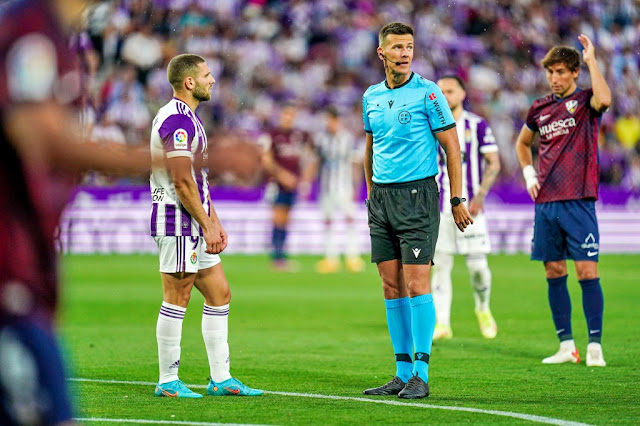 Shon Weissman y el árbitro Pulido Santana esperan el veredicto del VAR que acabó dando validez al gol del israelí. REAL VALLADOLID C. F. 3 S. D. HUESCA 0 Domingo 29/05/2022, 20:00 horas. Campeonato de Liga de 2ª División, jornada 42. Valladolid, estadio José Zorrilla: 22.397 espectadores.