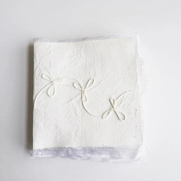 handmade book with thread bows stitched on white cover