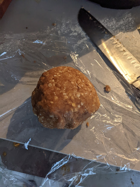 A lump of peanut butter dog biscuit dough, larger this time, on plastic wrap.