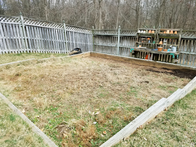 slanted yard with a wooden retaining wall in a square shape - back to woods