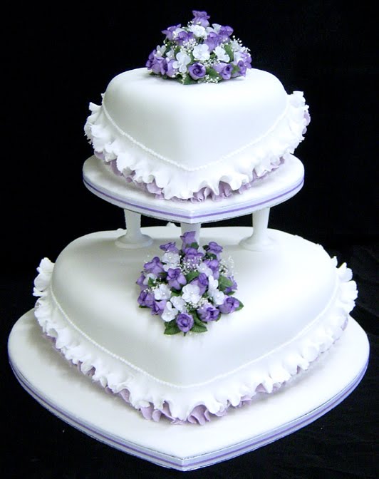 White heart shaped wedding cake with purple trimming and small purple and