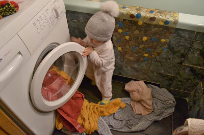 маленький ребенок в шапке в ванной комнате возле стиральной машинки