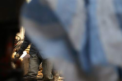 Image of a construction worker, in Hong Kong, glimpsed through a gap in a blue tarpaulin.