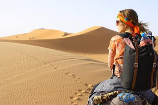 ラクダに乗って砂漠を移動する女性の写真