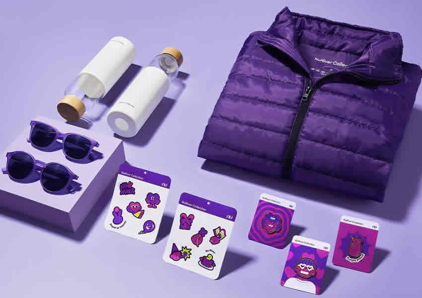 Imagem de fundo roxo claro mostra toda a coleção dos novos produtos do nubank composta por dois modelos de óculos um modelo de garrafinha uma jaqueta roxa e alguns adesivos.