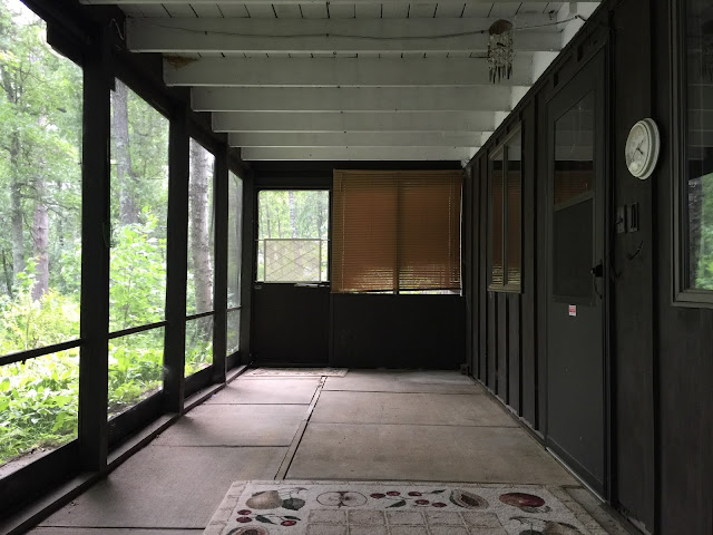 central Minnesota lakeside cabin home with dark exterior board and batten and screened in porch