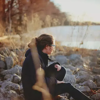 A girl sitting on  the stone near the pond- sad girl dp