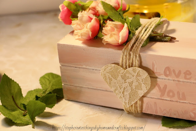 Close up of pink wooden crate with faux roses wrapped in twine