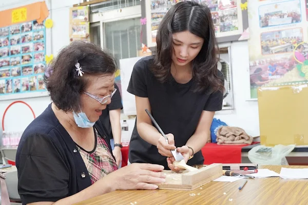▲大葉大學學生(右)耐心指導社區居民雕刻木湯匙。（大葉大學提供）