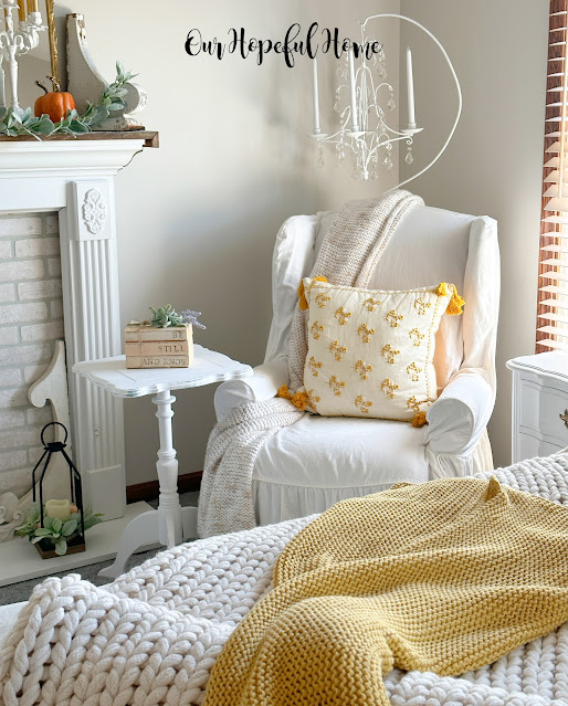 wingback chair with white slipcover and embroidered pillow.