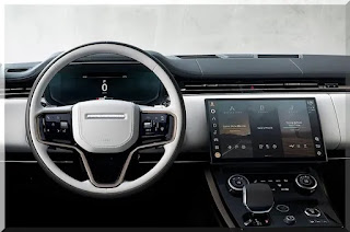 A foto apresenta o interior luxuoso do Range Rover Sport 2023, com acabamento em couro e detalhes em madeira e alumínio.