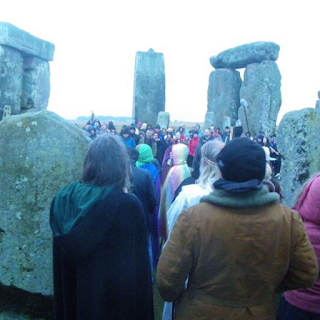 The back of a group of people at Stonehenge at dawn