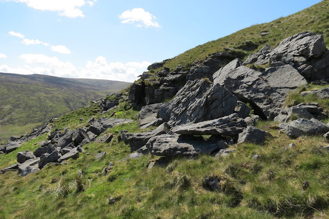 Exposed rocks near the top of Catlow Hill with a view to moorland in the background.