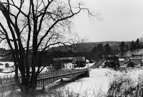 A black and white photograph of a bridge over a river.