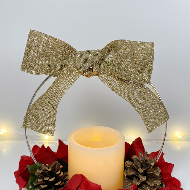 A close up of a gold bow on a Christmas hoop centerpiece.