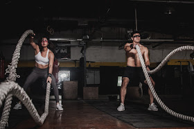 A man and a woman use ropes to exercise