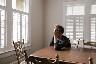 A man looking distressed, leaning on a table