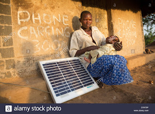 Mother with a solar panel in Lira District, Uganda, East Africa. (Credit: Alamy) Click to Enlarge.