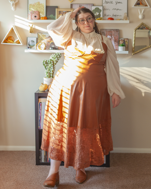 An outfit consisting of a cream Regency era inspired bishop sleeve blouse under a cognac brown midi dress and brown d'orsay flats