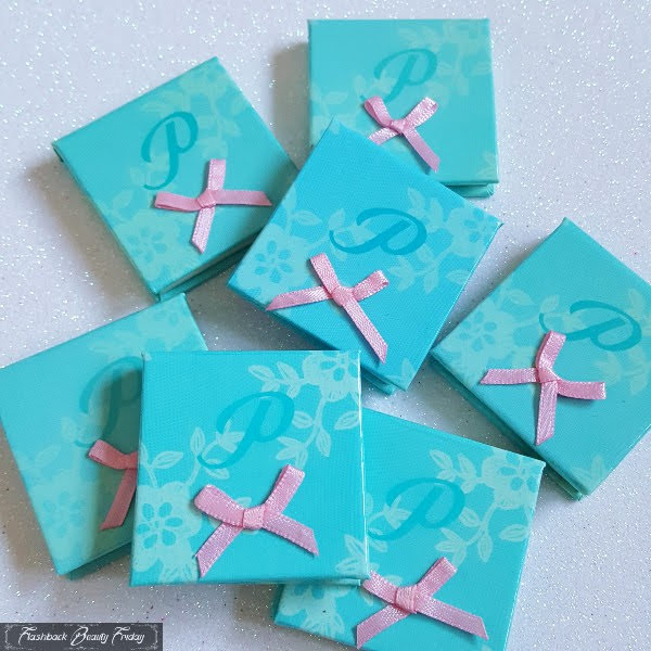 pile of pretty eyeshadow compacts in turquoise with pink ribbon bow