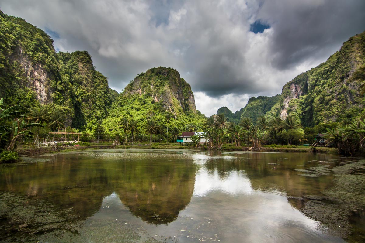 Limestone cliffs reflect in the water ponds in Berua Village, Rammang Rammang