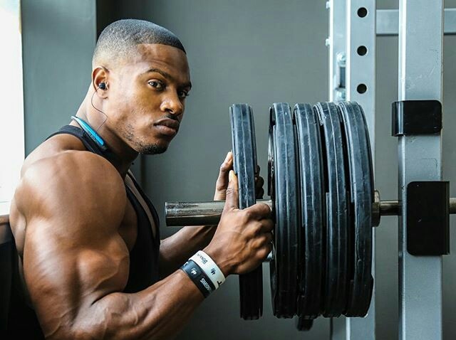 Hombre en el gimnasio cargando una barra con discos