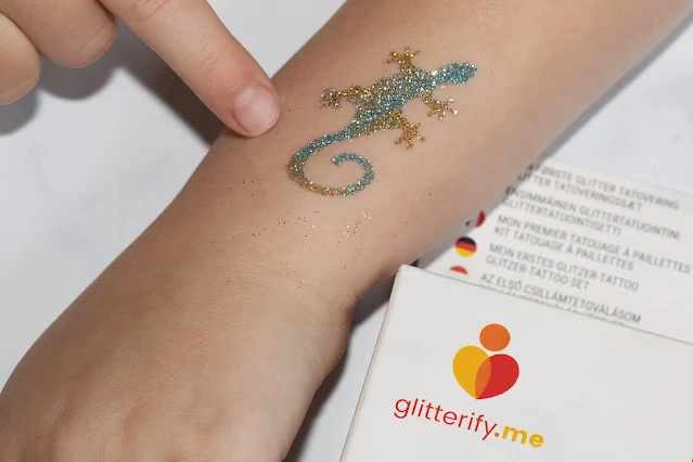 A lizard glitter tattoo in blue and gold on a child's arm from Glitterify Me