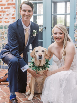 bride and groom kneeling and smiling with dog