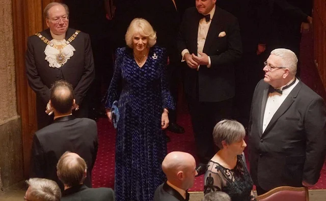 Queen Camilla wore a blue printed gown by Fiona Clare Aldridge. Van Cleef Arpels serpent necklace, vintage alhambra bracelet