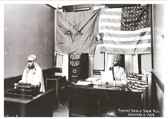 Prophet and Secretary in office with Moorish and American flags behind them