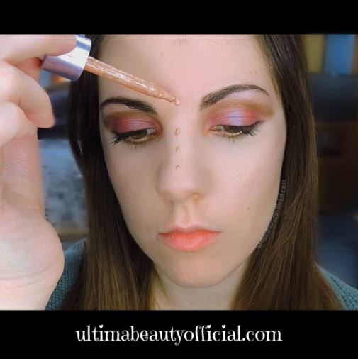 Ultima Beauty dotting liquid highlighter down bridge of nose with applicator.