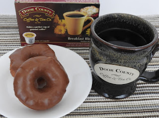 Chocolate frosted doughnuts on white plate with coffee