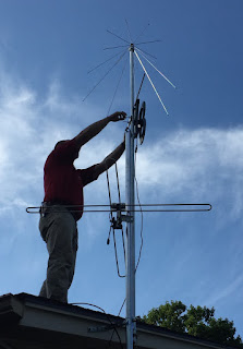 Chris on roof installing antenna on mast.