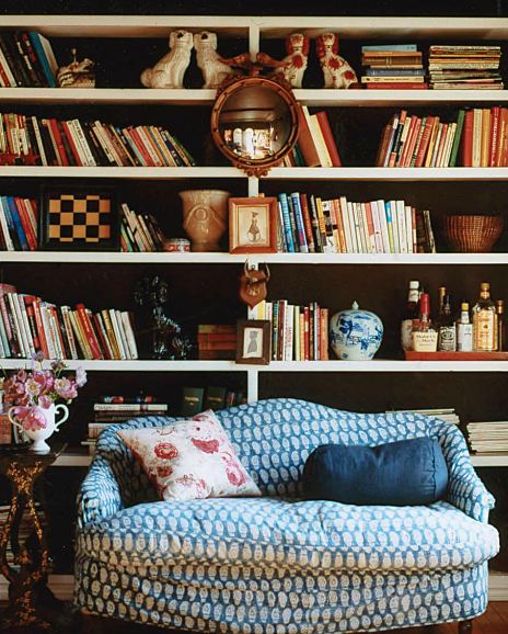 melanie acevedo's library with blue loveseat sofa with a built in bookshelf full of books