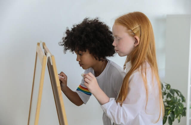 Two girls writing on a chalkboard