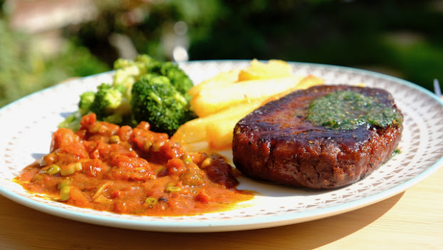 Vegan steak on a plate with chips and broccoli