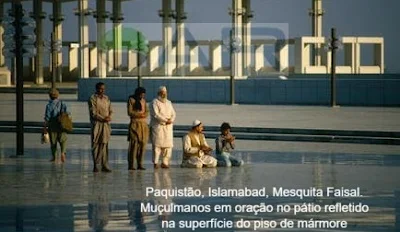 Paquistão, Islamabad, Mesquita Faisal. Muçulmanos em oração no pátio refletido na superfície do piso de mármore