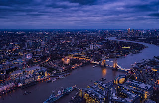 An image of a river in the middle of a city at night time. Bridges connect each side.