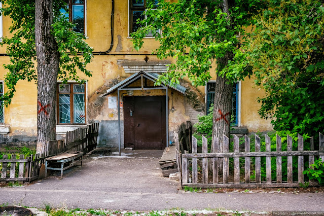 Подъезд дома, лавочки и деревья с крестами