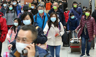 A group of people wearing masks at an airport to protect themselves from coronavirus