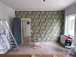 Foto van de slaapkamer met de eerste stukken behang. De overige muren worden egaal grijzig.