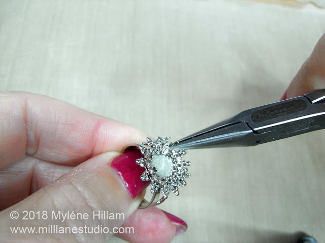 Use the chain nose pliers to open out the claws of the filigree ring base so the bead will fit.