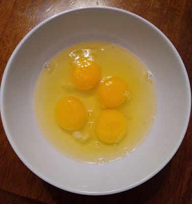 Four eggs, cracked into a bowl