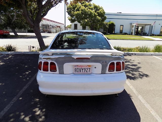 Original grey primer exposed where factory paint peeled on 1998 Ford Mustang.