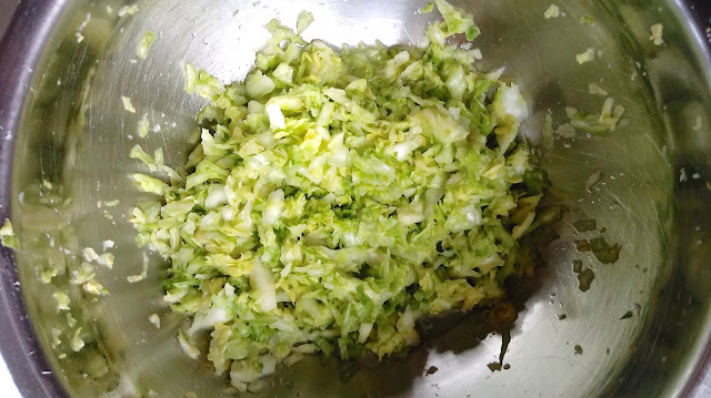 a large stainless steel bowl filled with massaged cabbage, ginger, and salt