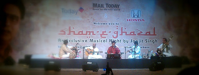 Mobile-giri at Sham-e-Ghazal with Jagjeet singh @ Sirifort Auditorium in Delhi (6th March 2011)  : posted by VJ SHARMA @ www.travellingcamera.com : Finally we got passes for today's Sham-e-Ghazal by Jagjeet Singh. We have been trying to see his live performance for last 6 years but we never managed to get tickets or invitation-Passes. This time, one of my friend arranged few passes for us and we had a lovely evening today ! Although it was but disappointing that cameras were not allowed inside :) ... but thanks to Adobe for gifting HTC Desire HD with nice Camera !!! So this was a good opportunity to try that in very low light conditions... Here are few photographs of Sham-e-Ghazal which are clicked with HTC Desire HD !!!HTC Desire provide various modes of clicking Photographs : Distortion, Vignette, Depth of Field, Sepia, Monochrome, Vintage, Vintage Warm, Vintage Cold, negative, Solarize, Polarize, Aqua !!!Photograph above is clicked using Sepia Mode and it was most suitable for Sham-e-Ghazal :)MAIL TODAY officials presenting flowers to Mr. Jagjeet Singh on his arrival at the stage !!!Mail Today organized Sham-e-Ghazal on 6th March at Sirifort Auditorium and it was planned to start at 6:00 pm... Plan was to close the gates by 5:45 pm and seat availability was on the basis of first come first serve !!! We reached at 5:15 pm and followed the queue.. I mean, started waiting for opening of gate !! There were very few folks at that time and people started coming. At 5:45 pm there were lot of Jagjeet fans in that queue...HONDA Officials presenting flowers to Mr. Jagjeet Singh !!!At 6:00 pm , gates were yet to be opened. It was bit surprising but there were no signs of opening the gates within next 15 mins.. There were two lines initially, one for men and other for women ! After 6:15 pm, few ladies came and started a new line. Other two lines were 300 meter long and people standing at the end started complaining about this third line. Security folks were very lazy and they didn't do anything even when many folks requested them to follow right practices. But no use !! Even people standing in third row were simply ignoring others.. All this didn't impact us because we were in the beginning of first two rows ! Manisha Dube introducing the man who don't need any introduction.. Mr. Jagjeet Singh !!!After standing for 2 hrs in a row, we got entry at 7:00 pm and program started at 7:40 pm !!! It was a great experience listening to Jagjeet Singh in Live show.. btw, we had VIP passes :) So he was very near to our seats !!! Wonderful performance by Jagjeet Singh and his troop of talented musicians !!!If you noticed these photographs, each has different effects and colors :) No editing, all are created in Camera only. HTC Desire HDIt was a good experience and want to Thank the friend who arranged passes for this event & Mail Today !!! But they need to be serious about the security and better planning !!