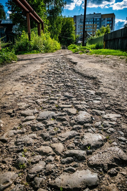 Булыжная мостовая выступает из-под асфальта