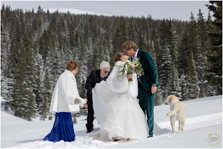 bride and groom kissing while parents fix dress and dog stands at their side